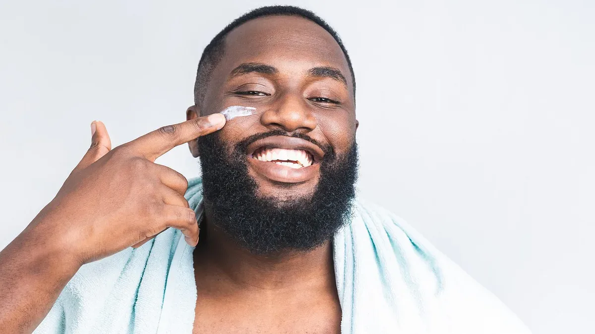 Mężczyzna nakłada krem na skórę twarzy przy nosie, pielęgnacja przy łojotokowym zapaleniu skóry twarzy